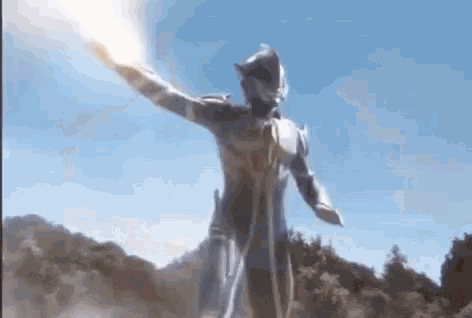 a man in a superhero costume is holding a flamethrower in his hand and flying through the air .