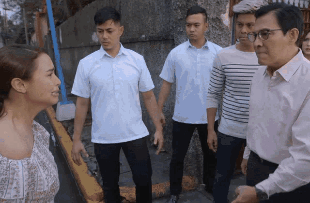 a group of men and a woman are standing next to each other on a sidewalk