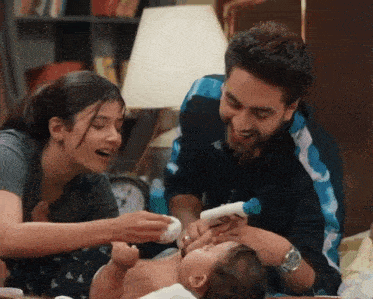 a man and woman are feeding a baby with a bottle