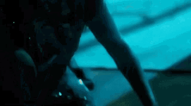 a woman is swimming underwater in a swimming pool in the dark .