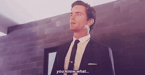 a man in a suit and tie is standing in a room and saying `` you know what '' .