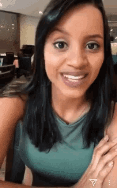 a woman in a green tank top is smiling with a triangle tattoo on her arm