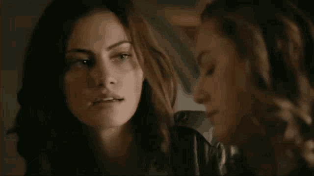 two women are standing next to each other and looking at each other in a dark room .