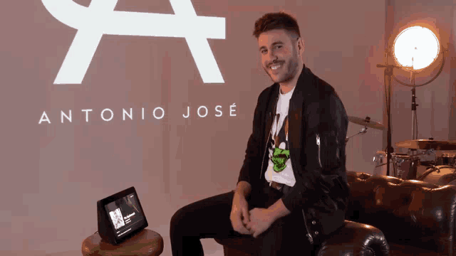 a man sits on a couch in front of an antonio jose sign