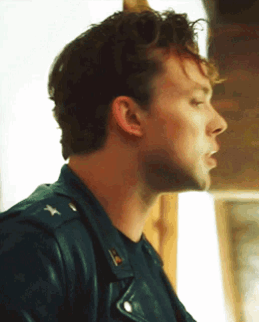 a close up of a man 's face with a leather jacket on