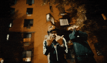 two men standing in front of a building with their hands in the air
