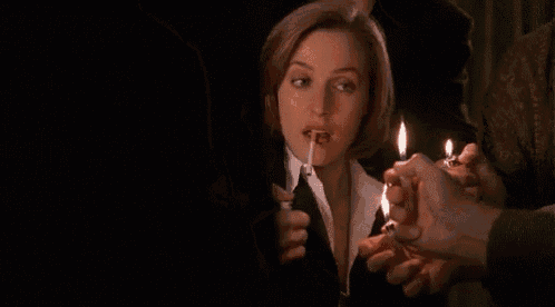 a woman is lighting a cigarette with a lighter in her mouth while a group of people hold lit candles .