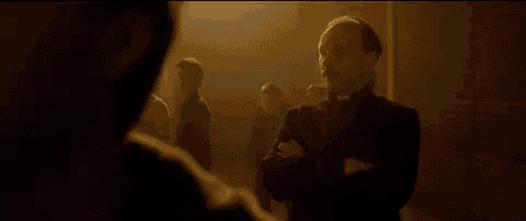 a priest is standing in front of a group of people in a dark room .