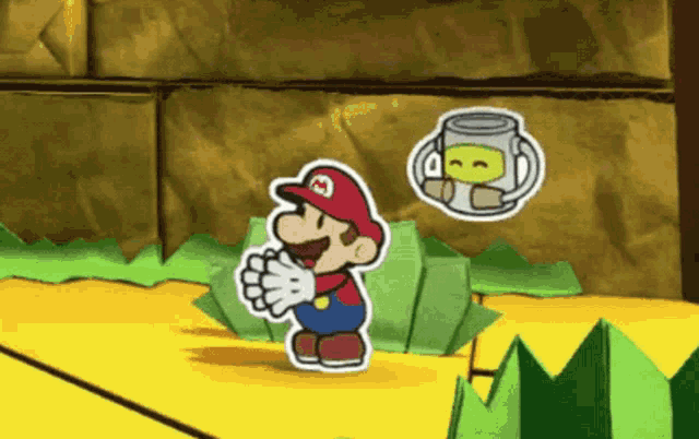 a paper mario with a m on his hat stands in front of a cup