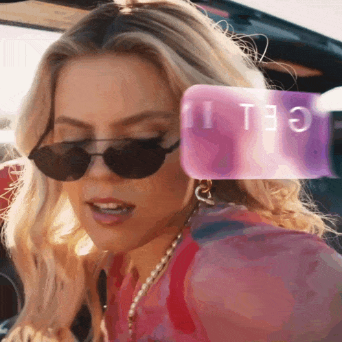 a woman wearing sunglasses and a pink cell phone behind her