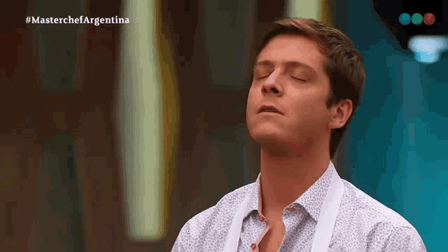 a man with his eyes closed in front of a masterchef argentina sign