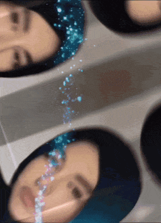 a woman 's face is reflected in a mirror with blue sparkles