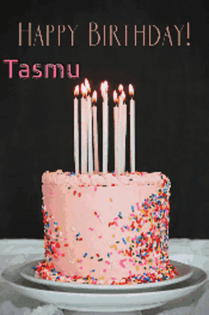 a pink birthday cake with candles and sprinkles is on a plate