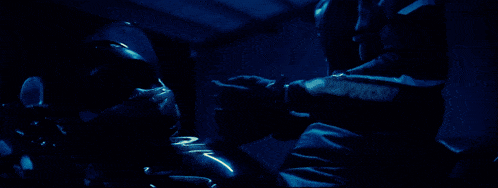 a man wearing a jacket that says ' alpinestars ' on it stands in a dark room
