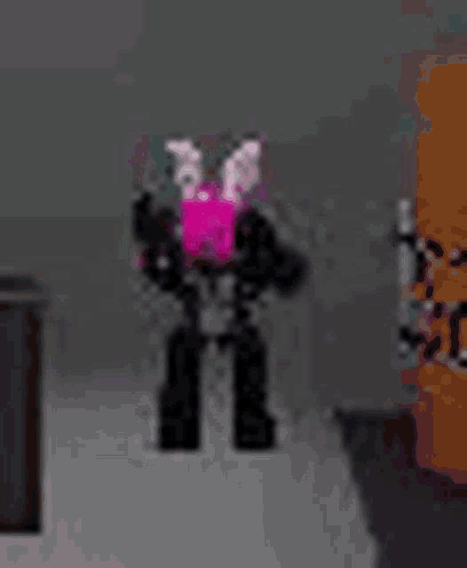 a robot with a pink bunny costume is standing in a room next to a halloween decoration .