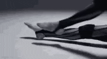 a black and white photo of a person doing a yoga pose on the floor .