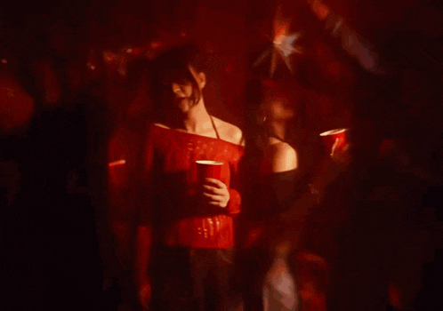a woman in a red shirt is holding a red cup