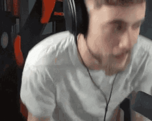 a man wearing headphones and a white t-shirt is sitting in a chair with the word bmc on it