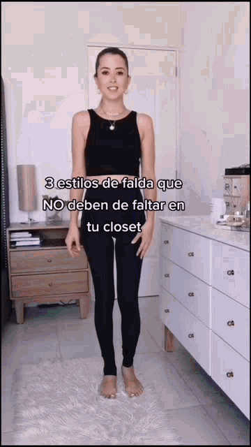 a woman wearing a black tank top and black leggings is standing in front of a white dresser