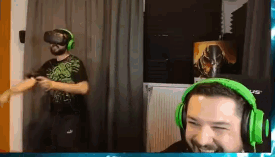 a man wearing green headphones is smiling while another man wearing a virtual reality headset looks on