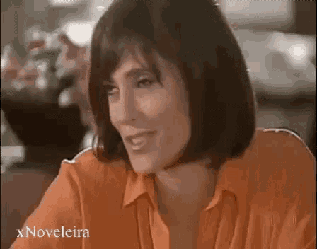 a woman in an orange shirt is smiling at the camera .
