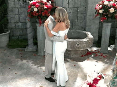 a bride and groom kissing in front of a stone fountain