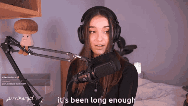 a woman wearing headphones stands in front of a microphone with the words " it 's been long enough " below her