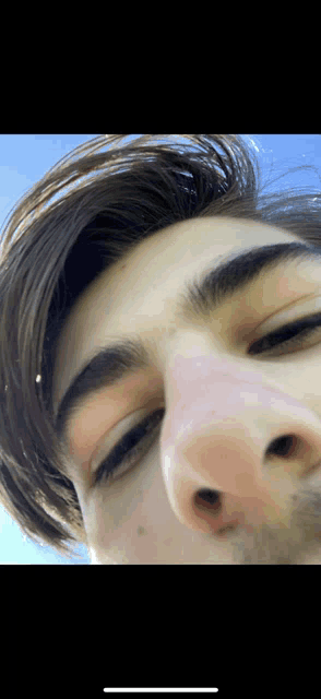 a close up of a person 's face with a blue sky in the background