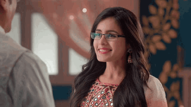 a woman wearing glasses smiles at a man