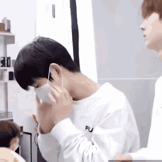 a man wearing a white sweatshirt is putting on a white mask .