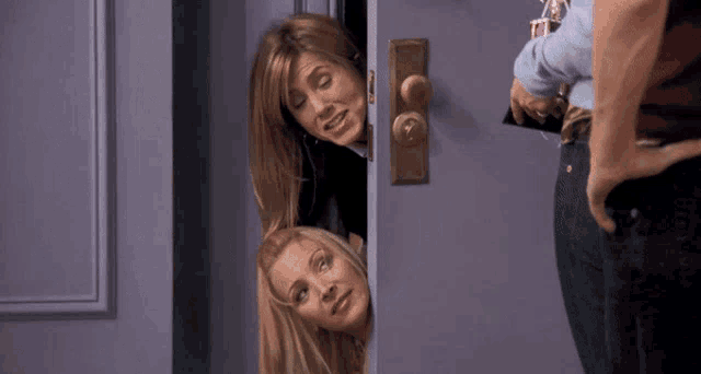 two women peeking out of a purple door with a man standing behind them