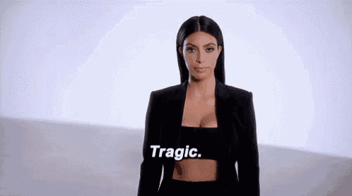 a woman in a black suit is standing in front of a white background .