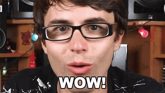 a man wearing glasses is making a surprised face and says wow