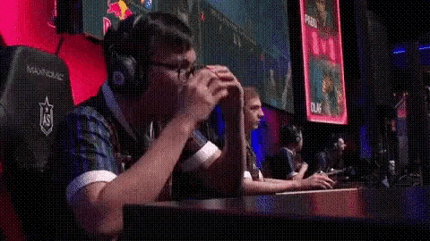 a man is sitting in a gaming chair with his hands on his face .