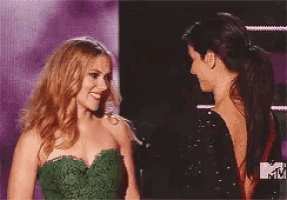 a woman in a green dress talks to another woman