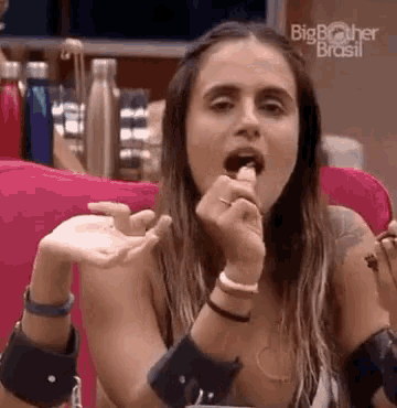 a woman is sitting on a couch eating a piece of food with her mouth open .