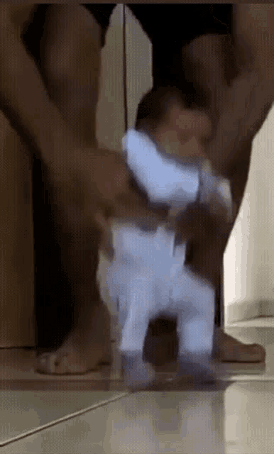 a man is holding a baby in his arms who is walking