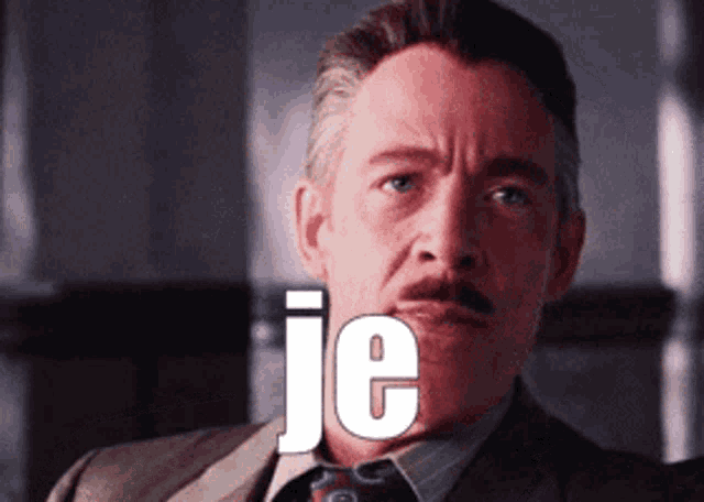 a man wearing a suit and tie with the word je on his face
