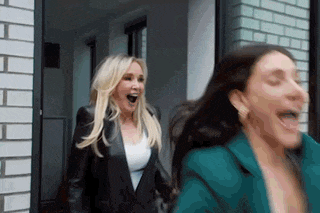 two women are running in front of a brick building .