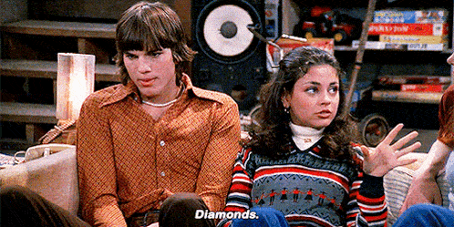 a man and a woman are sitting on a couch talking to each other and the woman is saying `` diamonds '' .