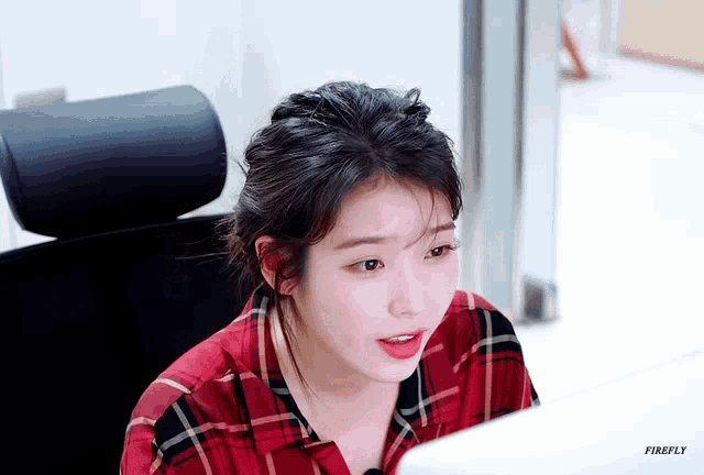 a woman in a red plaid shirt is sitting in front of a computer screen with firefly written on the bottom