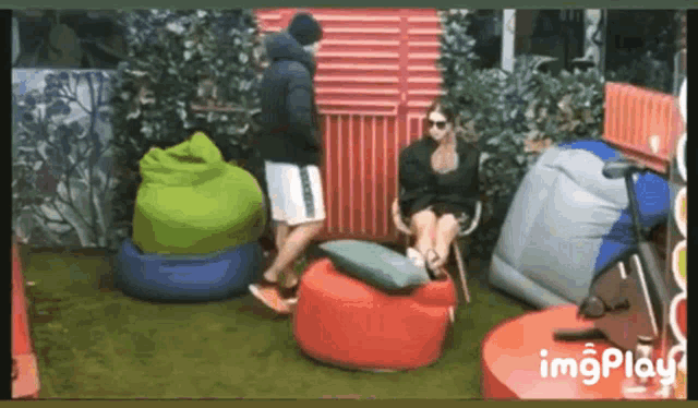 a woman is sitting on a bean bag chair while a man stands behind her