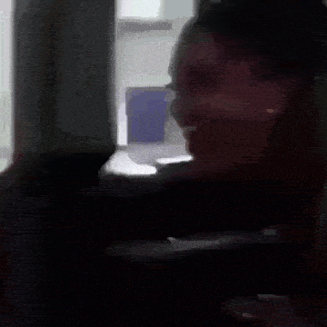 a woman is screaming in a dark room while sitting in a chair .