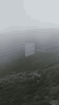 a foggy hillside with a white building in the middle
