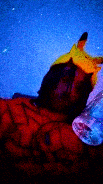 a person wearing a pikachu hat is laying down with a bottle of water next to them