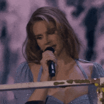 a woman in a blue dress is holding a microphone and singing into it .