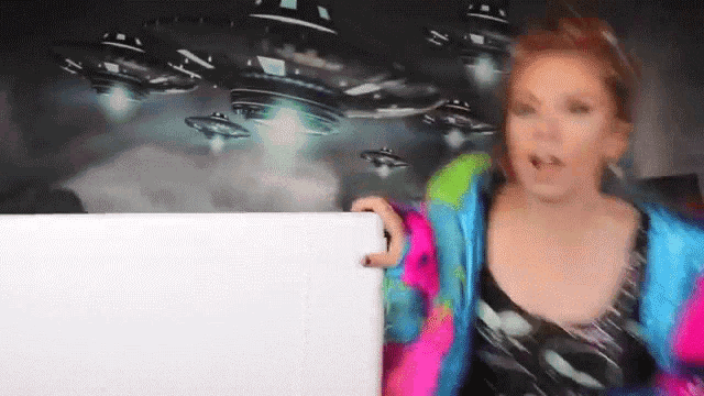 a woman in a colorful jacket is holding a white board