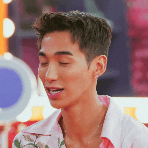 a close up of a man 's face with his eyes closed and a pink shirt on