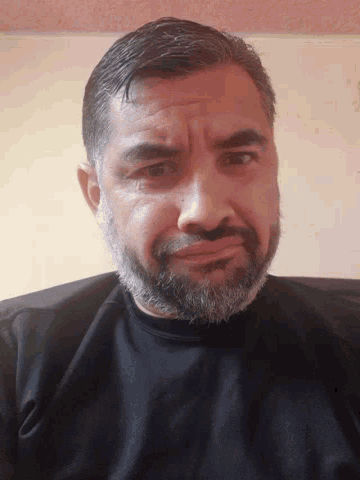 a man with a beard wearing a black shirt looks at the camera