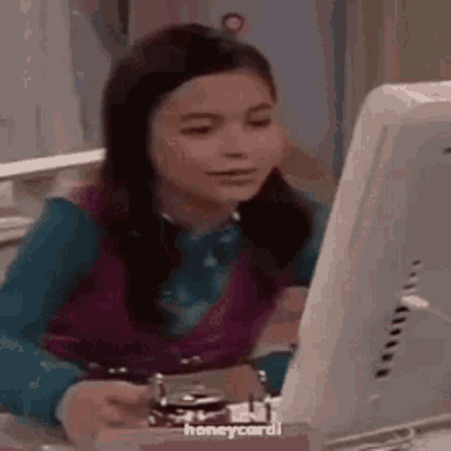a girl is sitting at a desk in front of a computer monitor .